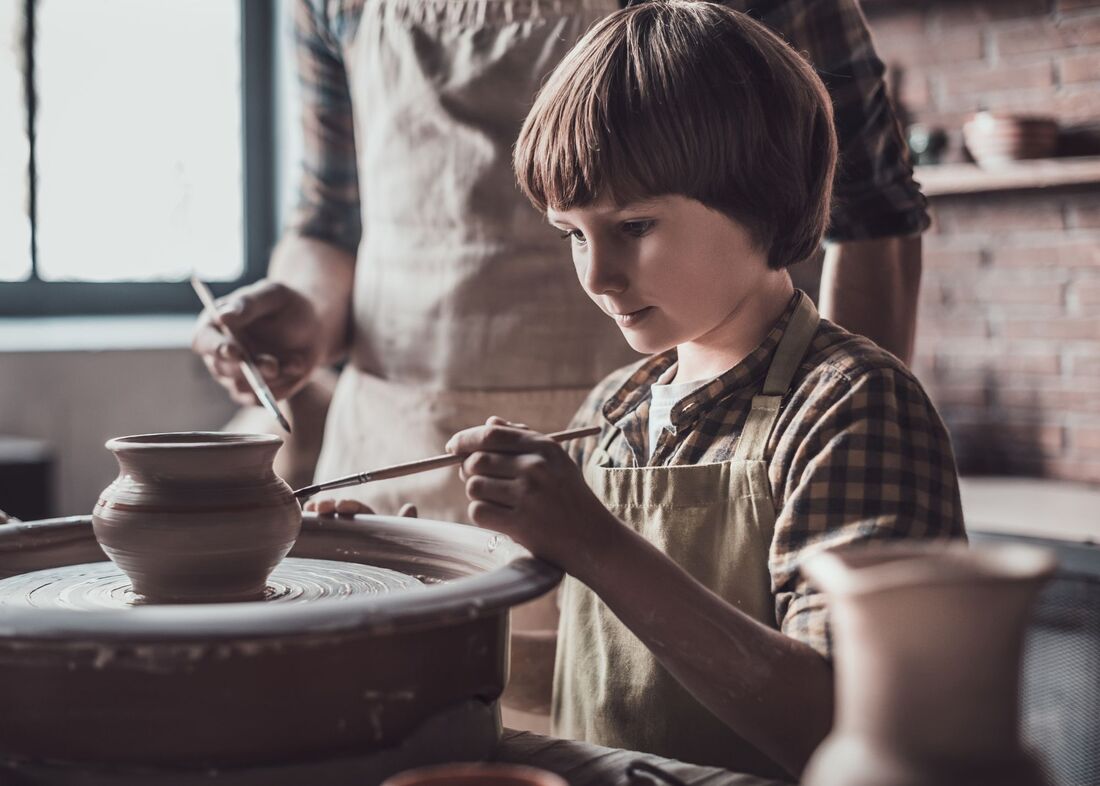 A boy learning to do pottery.  