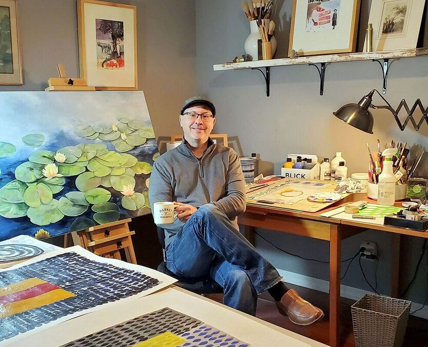 This is a photo of artist, Bruce Black in his art studio.  There is a painting of water lilies behind him.