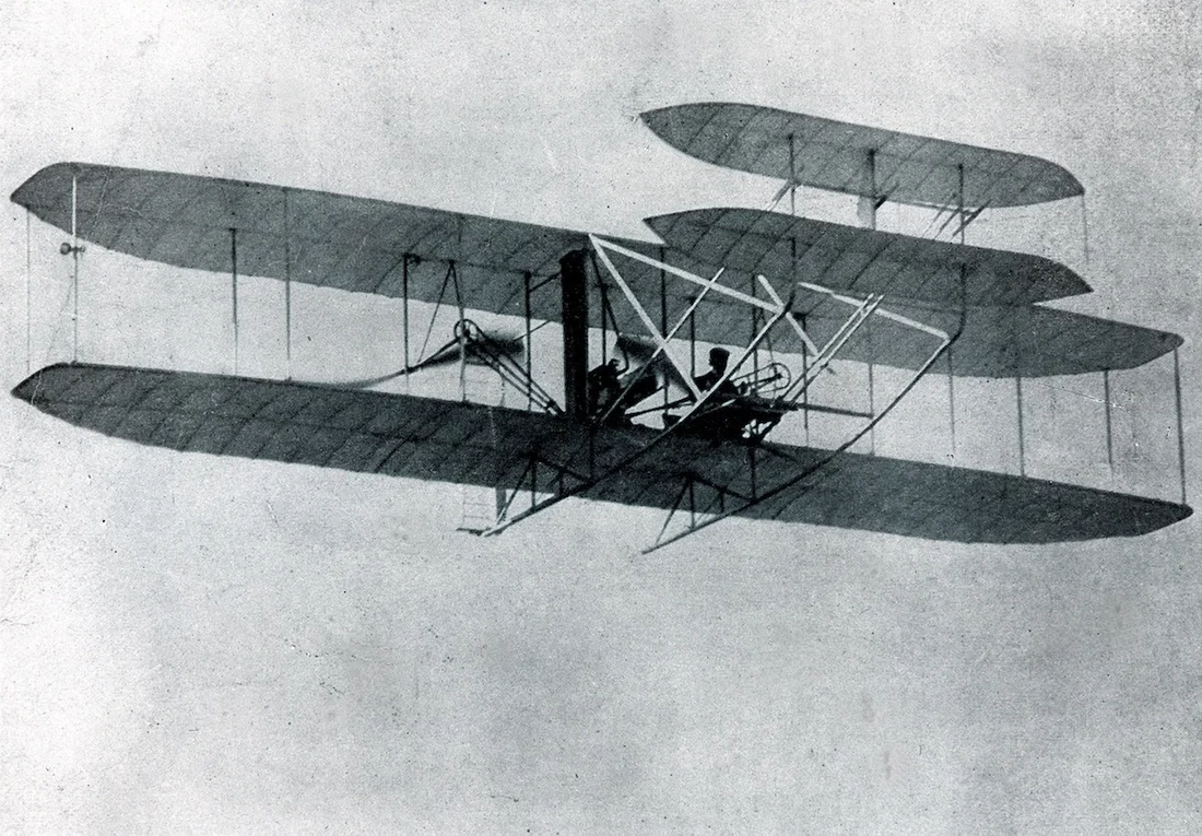 Black and white photo of first airplane flying 